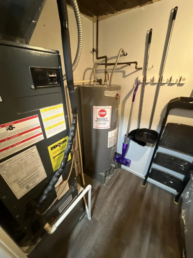 Utility closet showing a new HVAC air handler unit and a new Rheem electric water heater with piping, alongside cleaning tools and a step stool on luxury vinyl plank flooring